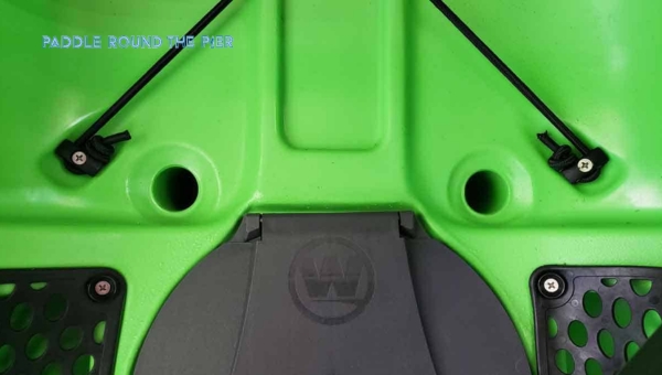 Close-up of a green kayak showing the scupper plugs and seat area