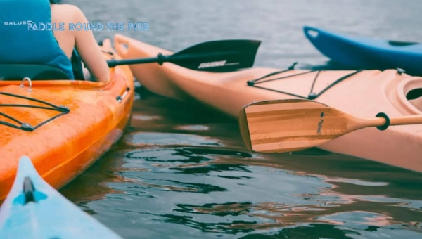 Three colorful kayaks with paddles on calm water, depicting kayak weight as a factor for maneuverability.
